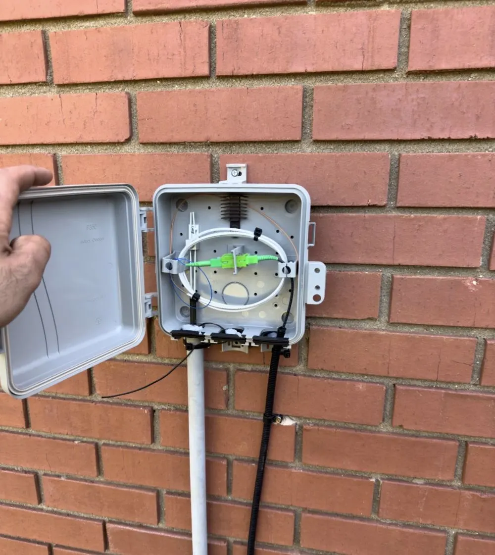 Exterior fiber-optic termination enclosure mounted on a brick wall